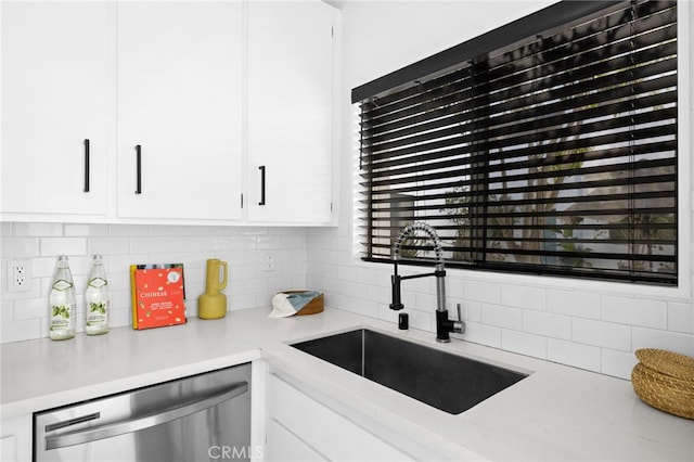 kitchen featuring tasteful backsplash, sink, stainless steel dishwasher, and white cabinets