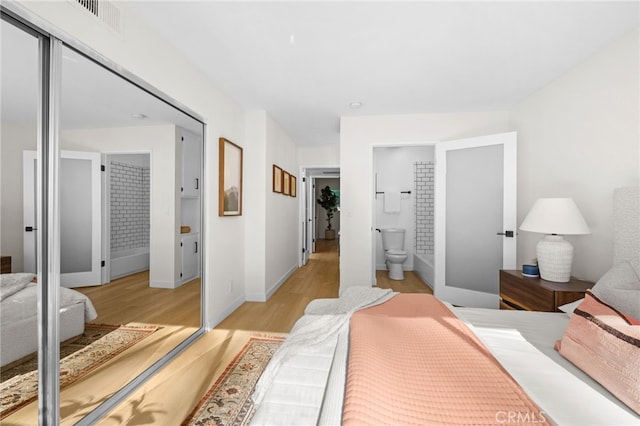 bedroom featuring ensuite bath and light wood-type flooring