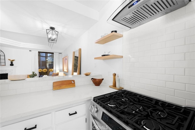 kitchen featuring premium range hood, an inviting chandelier, stainless steel range with gas stovetop, white cabinets, and decorative backsplash