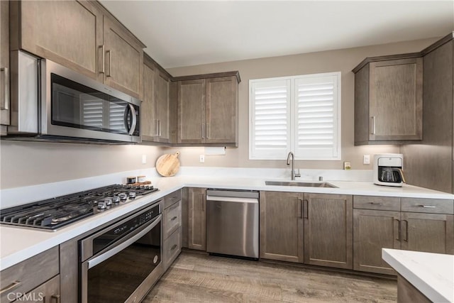 kitchen featuring stainless steel appliances, sink, and light hardwood / wood-style flooring