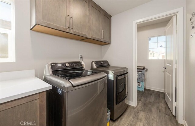 clothes washing area featuring cabinets, dark hardwood / wood-style floors, and washing machine and dryer