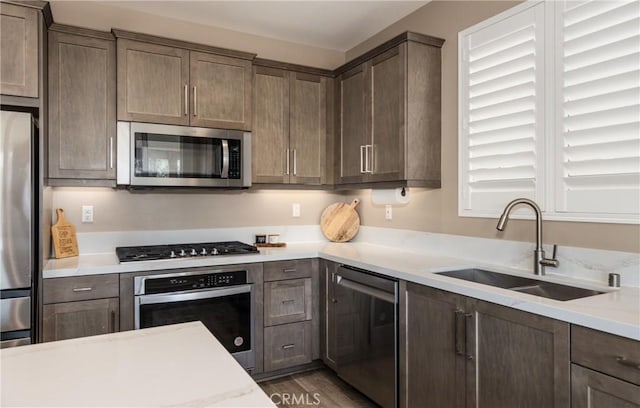 kitchen with appliances with stainless steel finishes, sink, dark hardwood / wood-style floors, and dark brown cabinets