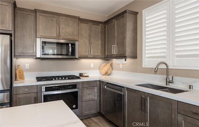 kitchen with wood finished floors, stainless steel appliances, a sink, and light countertops