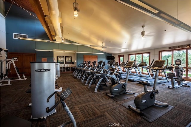 workout area with ceiling fan, dark carpet, and high vaulted ceiling