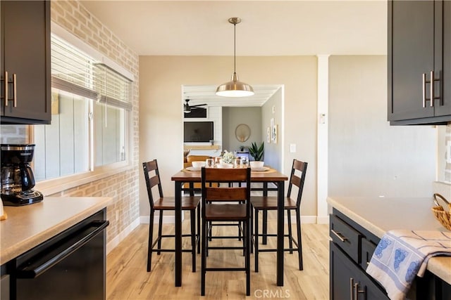 dining area with ornate columns, ceiling fan, brick wall, and light wood-type flooring