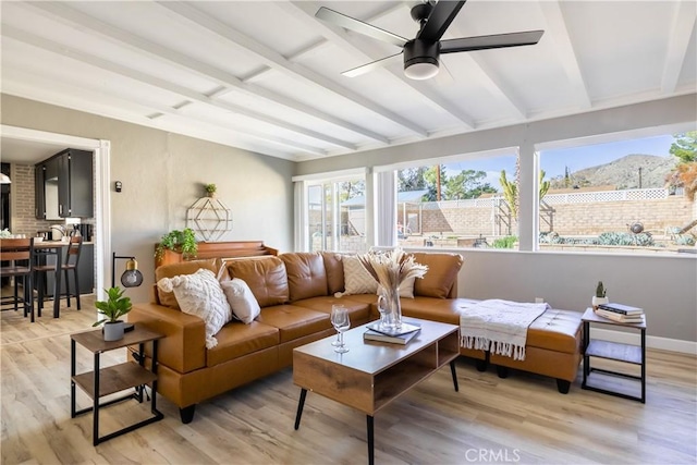 sunroom / solarium featuring a mountain view, beam ceiling, and ceiling fan