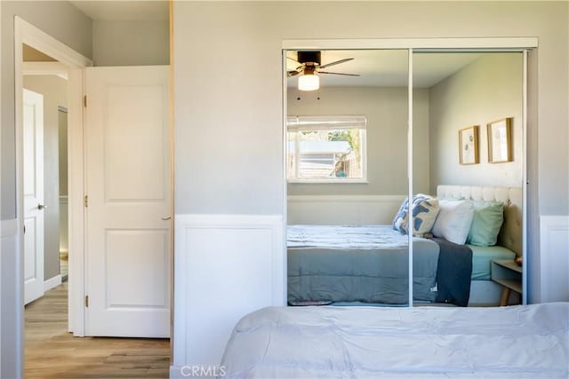 bedroom with light hardwood / wood-style flooring, ceiling fan, and a closet