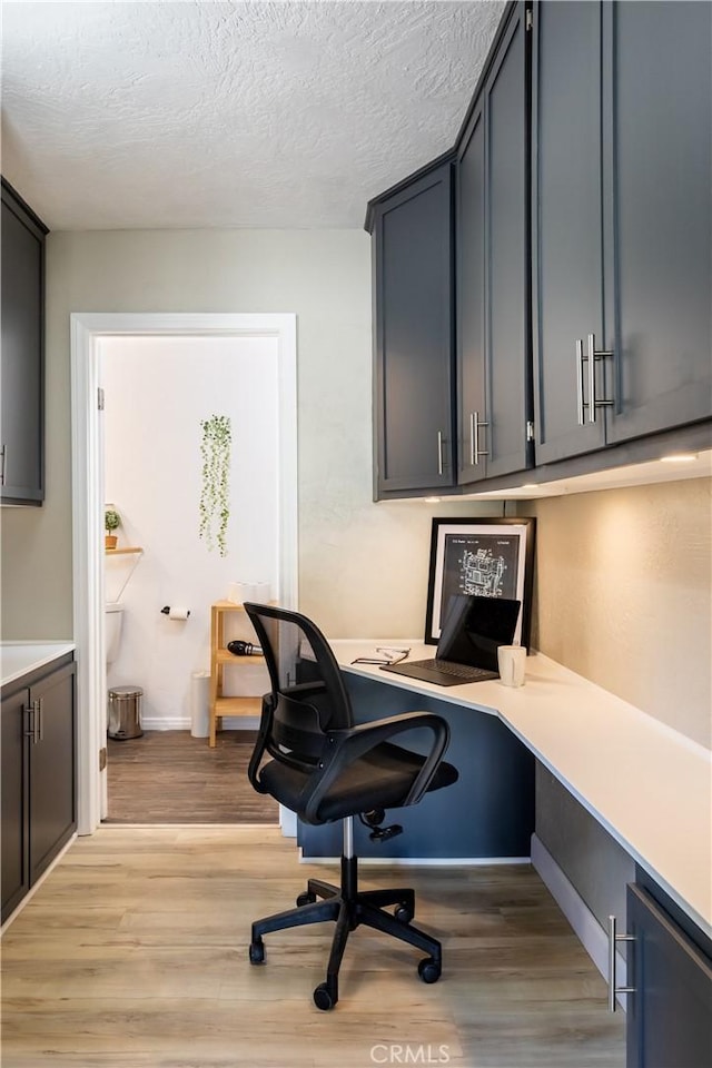 home office featuring a textured ceiling and light hardwood / wood-style floors