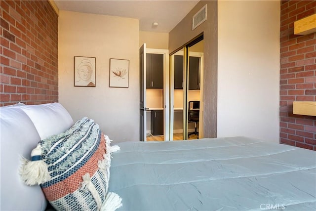 bedroom featuring brick wall and a closet