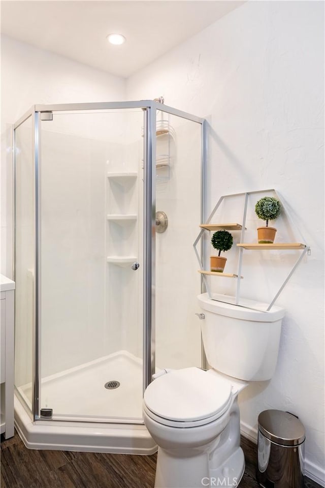 bathroom with walk in shower, toilet, and hardwood / wood-style floors