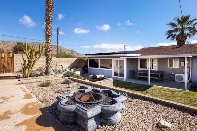 rear view of property featuring solar panels, a patio, ac unit, and an outdoor fire pit