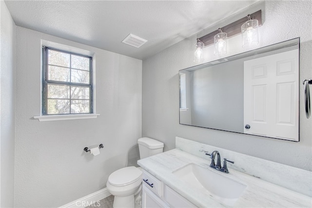 bathroom with vanity, toilet, and a textured ceiling