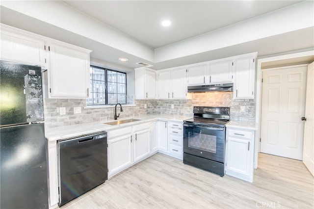 kitchen with sink, light hardwood / wood-style flooring, tasteful backsplash, black appliances, and white cabinets