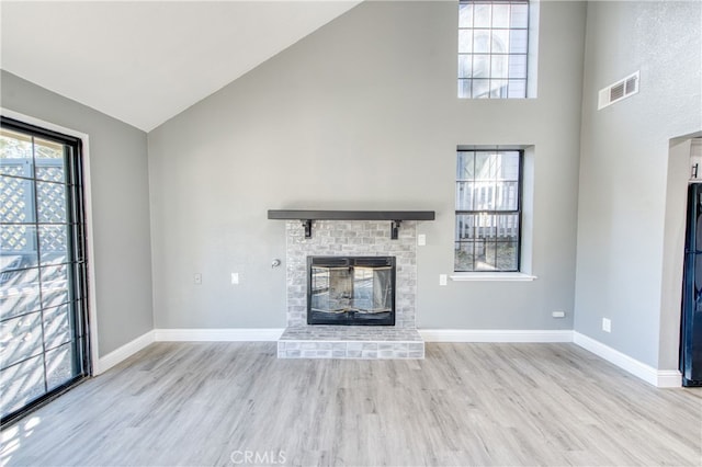 unfurnished living room featuring light hardwood / wood-style flooring, a fireplace, and high vaulted ceiling