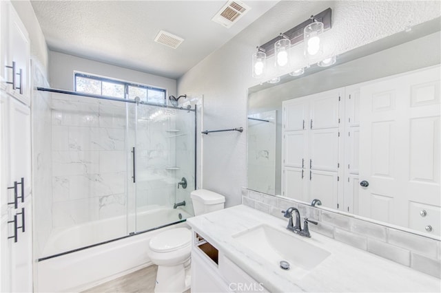 full bathroom with toilet, vanity, shower / bath combination with glass door, and a textured ceiling