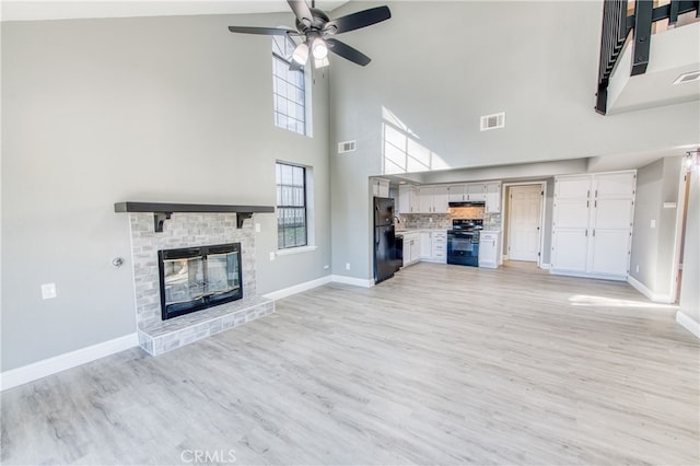 unfurnished living room with a high ceiling, light wood-type flooring, a wealth of natural light, and a fireplace