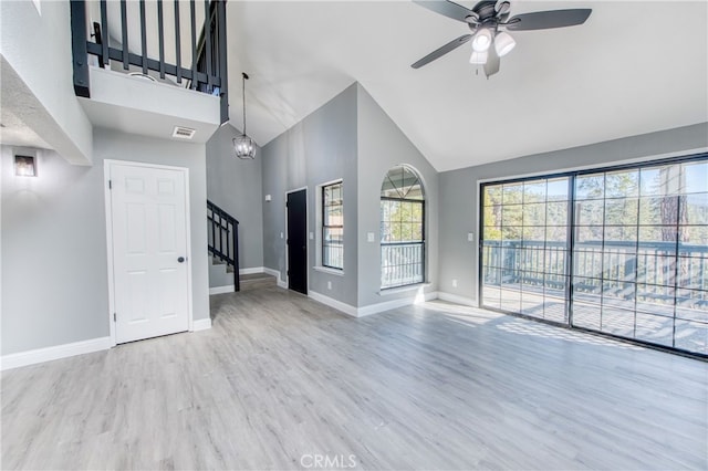 unfurnished living room featuring high vaulted ceiling, ceiling fan with notable chandelier, and light wood-type flooring