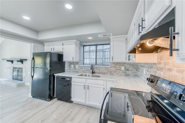 kitchen with sink, white cabinetry, backsplash, a tray ceiling, and black appliances