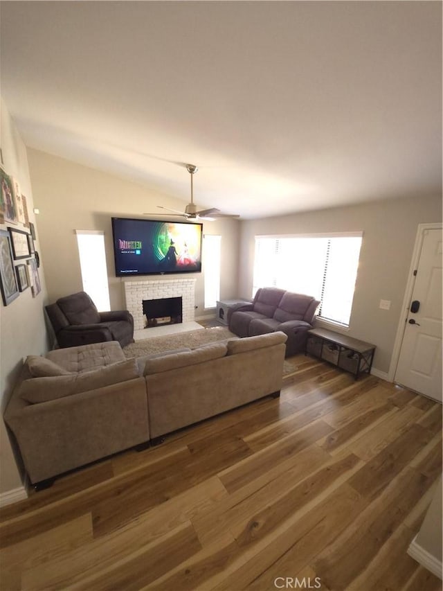 living room featuring dark hardwood / wood-style floors, ceiling fan, lofted ceiling, and a fireplace