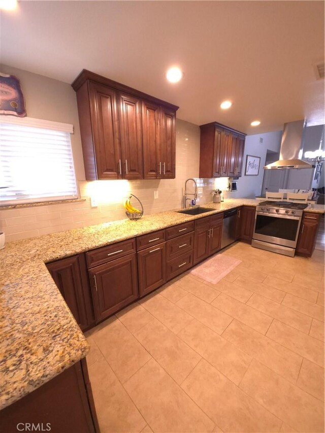 kitchen with island exhaust hood, stainless steel appliances, light stone countertops, and sink