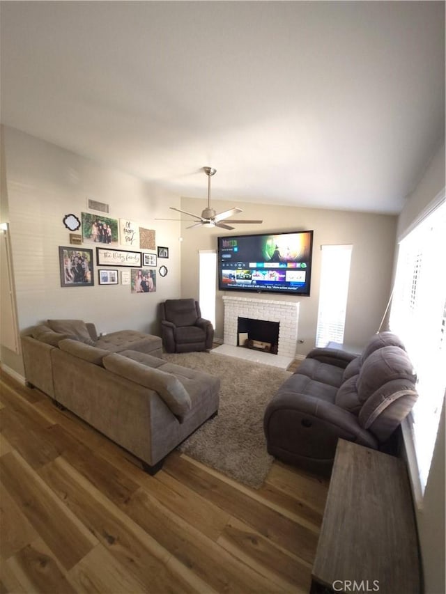 living room with ceiling fan, lofted ceiling, hardwood / wood-style floors, and a fireplace