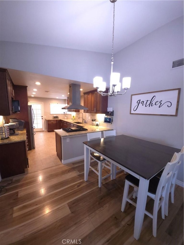 dining area featuring lofted ceiling, sink, light hardwood / wood-style floors, and a chandelier