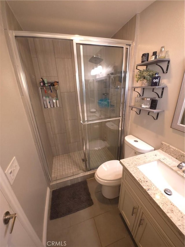 bathroom with toilet, vanity, a shower with door, and tile patterned flooring