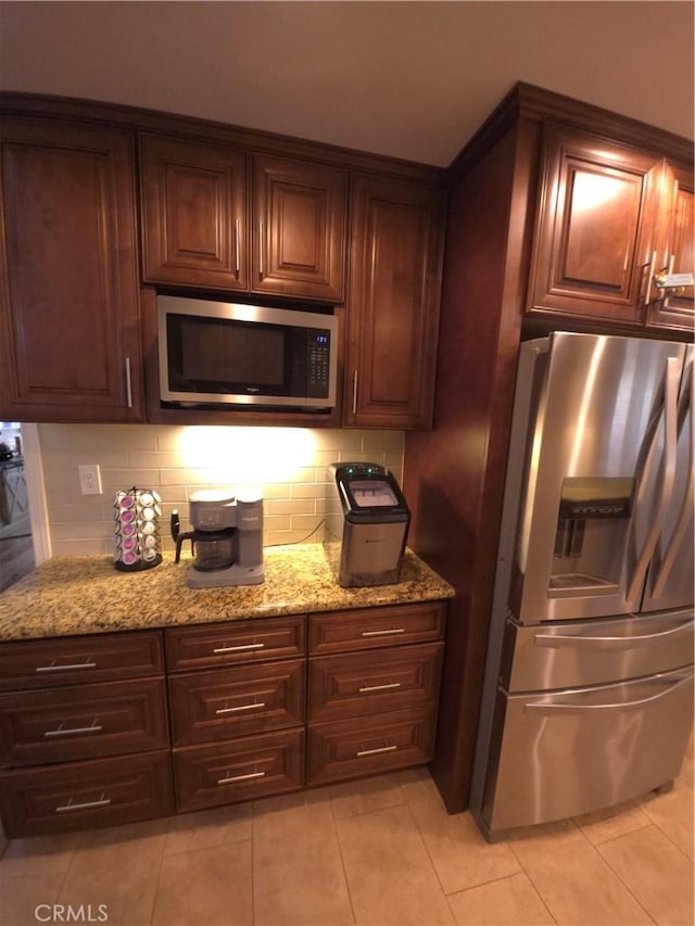 kitchen featuring light stone counters, light tile patterned floors, backsplash, and stainless steel appliances