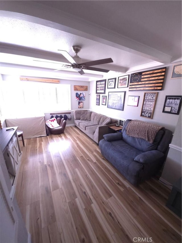 living room with beam ceiling, hardwood / wood-style flooring, a textured ceiling, and ceiling fan