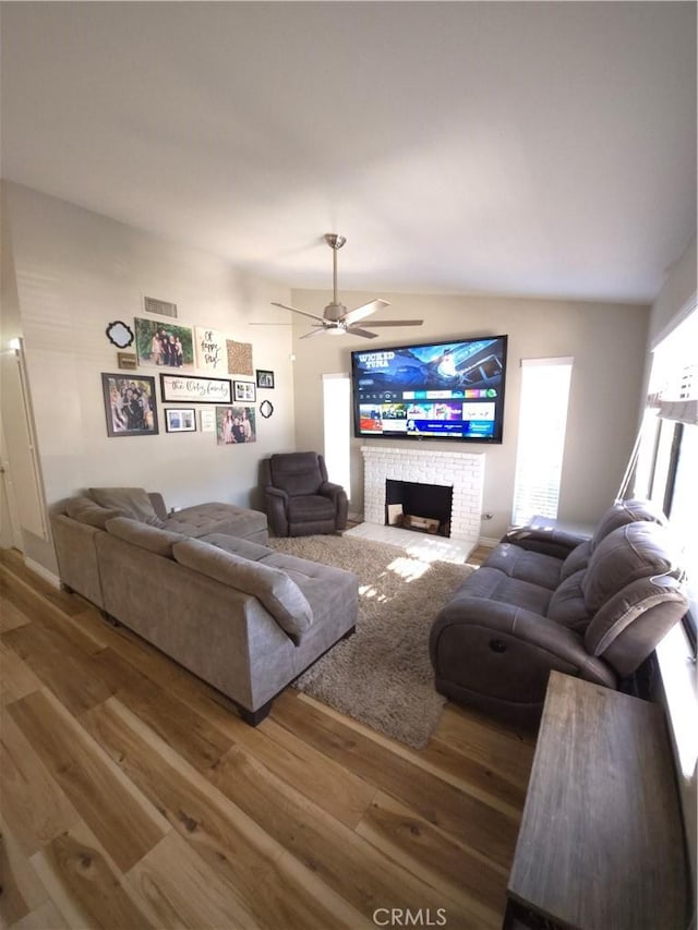 living room with hardwood / wood-style flooring, ceiling fan, plenty of natural light, and a brick fireplace