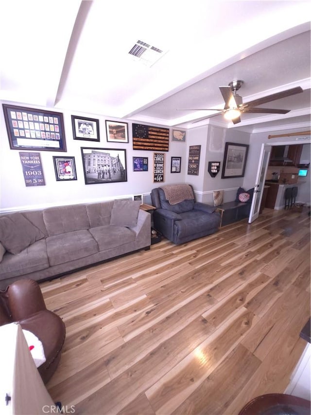 living room with beam ceiling, wood-type flooring, and ceiling fan