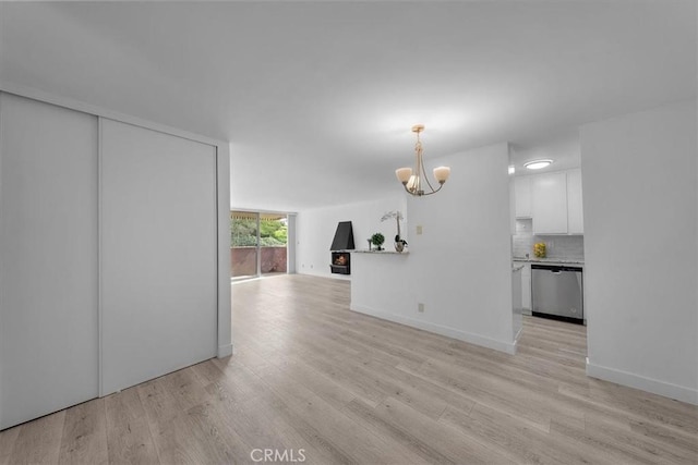 unfurnished living room featuring an inviting chandelier and light hardwood / wood-style floors