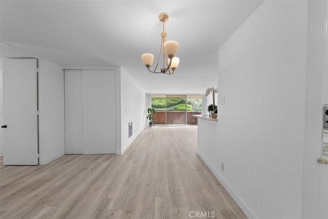 corridor with an inviting chandelier, light hardwood / wood-style flooring, and expansive windows