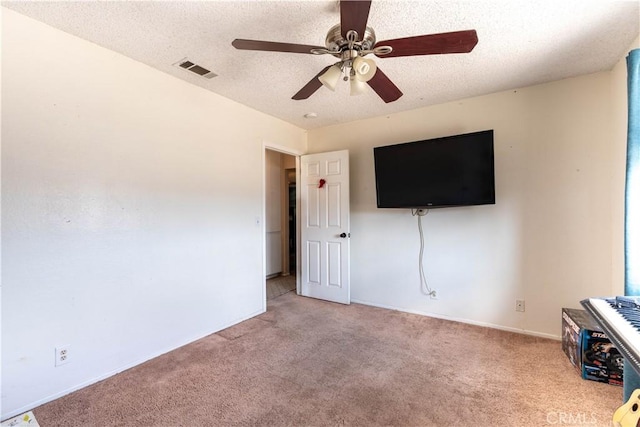 unfurnished living room with ceiling fan, carpet flooring, visible vents, and a textured ceiling