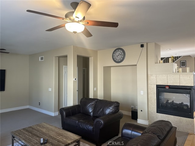 living room with ceiling fan and a tiled fireplace