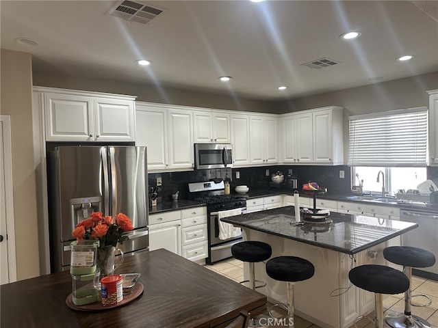 kitchen with sink, light tile patterned floors, appliances with stainless steel finishes, white cabinets, and a kitchen island