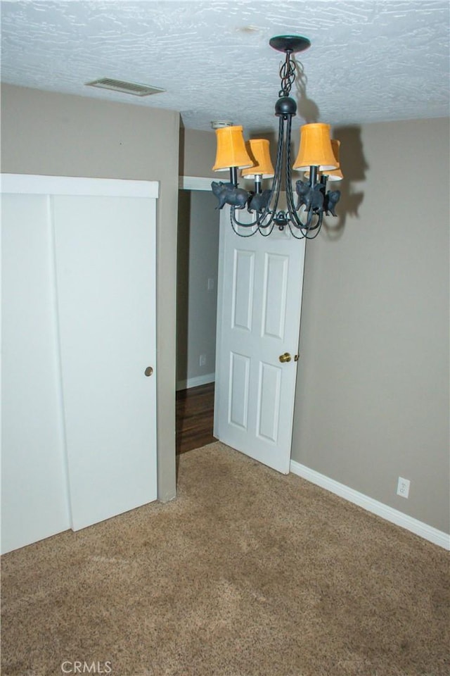 unfurnished dining area featuring a textured ceiling and carpet flooring