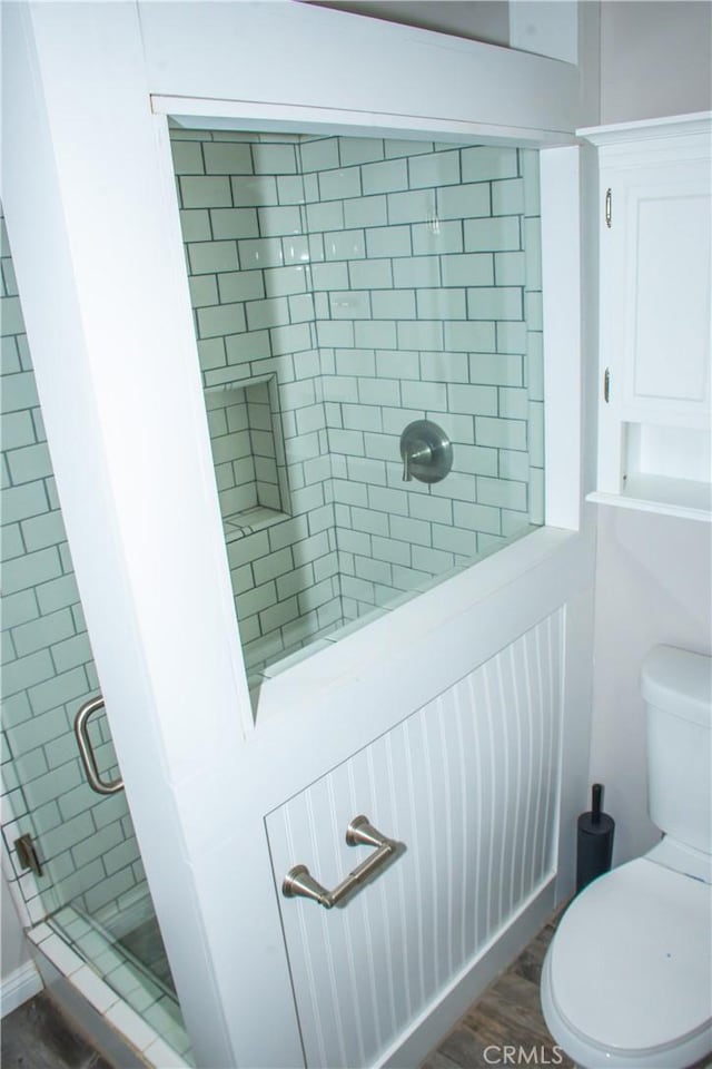 bathroom featuring wood-type flooring, an enclosed shower, and toilet