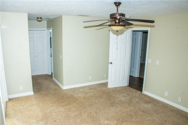 unfurnished bedroom with light carpet, a textured ceiling, and ceiling fan