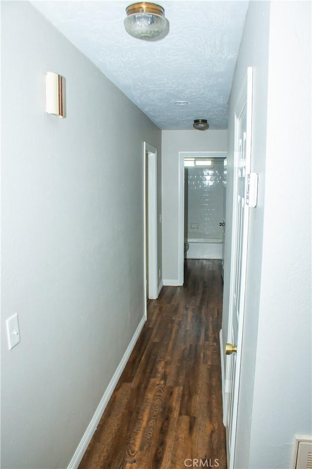 corridor featuring dark wood-type flooring and a textured ceiling