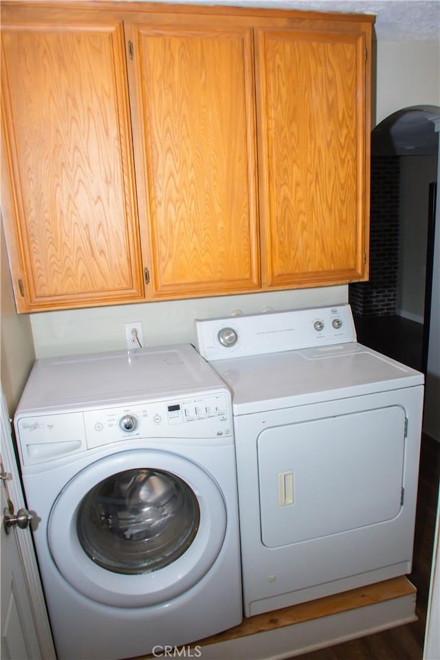 washroom featuring dark wood-type flooring, cabinets, and washing machine and clothes dryer