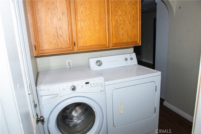 laundry room with cabinets, washer and dryer, and dark wood-type flooring