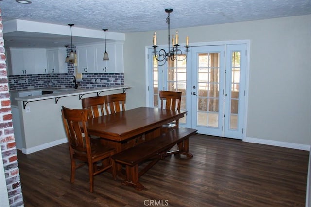 dining room with dark hardwood / wood-style flooring, sink, a textured ceiling, and an inviting chandelier