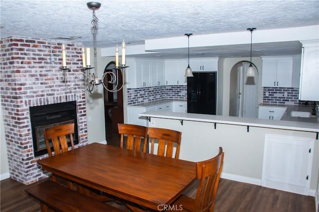 dining area featuring a brick fireplace, sink, dark hardwood / wood-style floors, and a textured ceiling