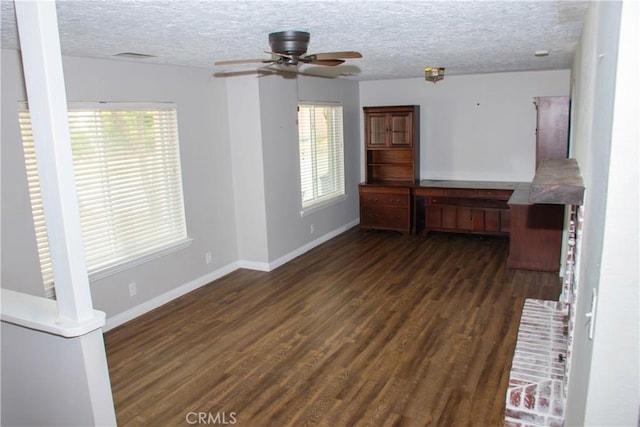 spare room with a healthy amount of sunlight, dark wood-type flooring, ceiling fan, and a textured ceiling