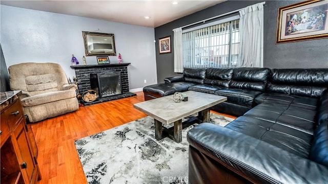 living room featuring a brick fireplace and wood-type flooring