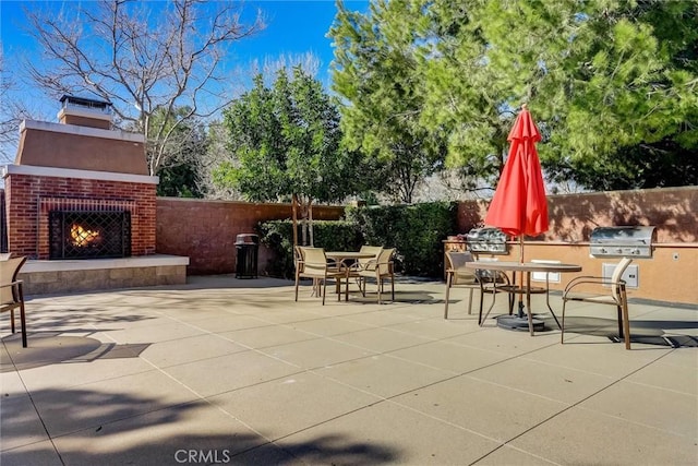 view of patio featuring an outdoor brick fireplace and grilling area