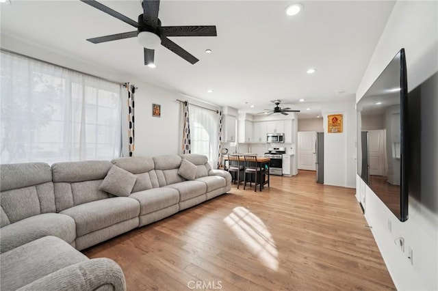 living room with ceiling fan and light wood-type flooring