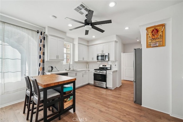 kitchen featuring light wood-type flooring, stainless steel appliances, sink, and white cabinets