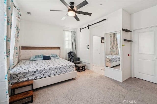 carpeted bedroom with a barn door and ceiling fan